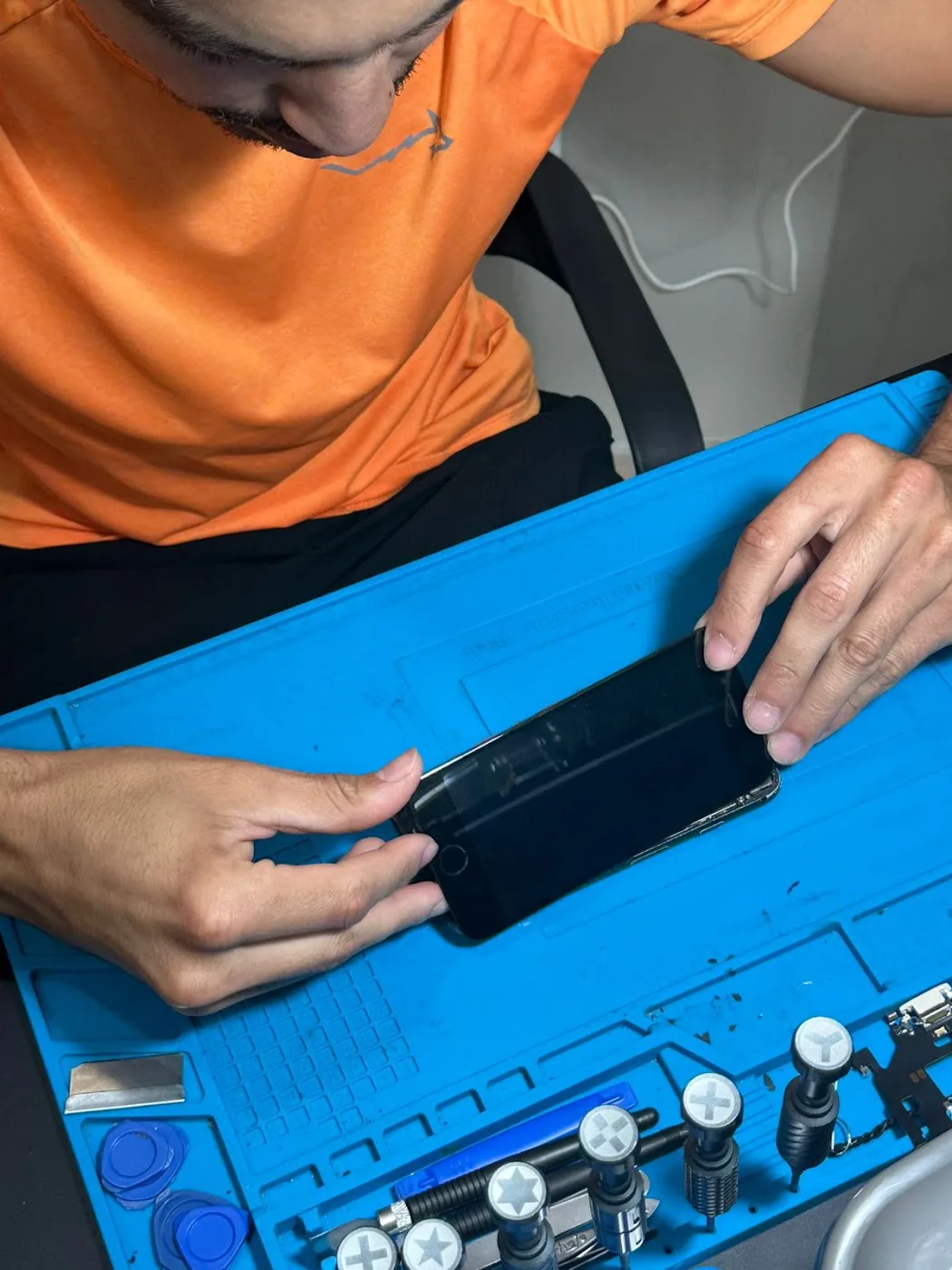 Profissional da Campeche Cell trabalhando em um celular sobre a bancada