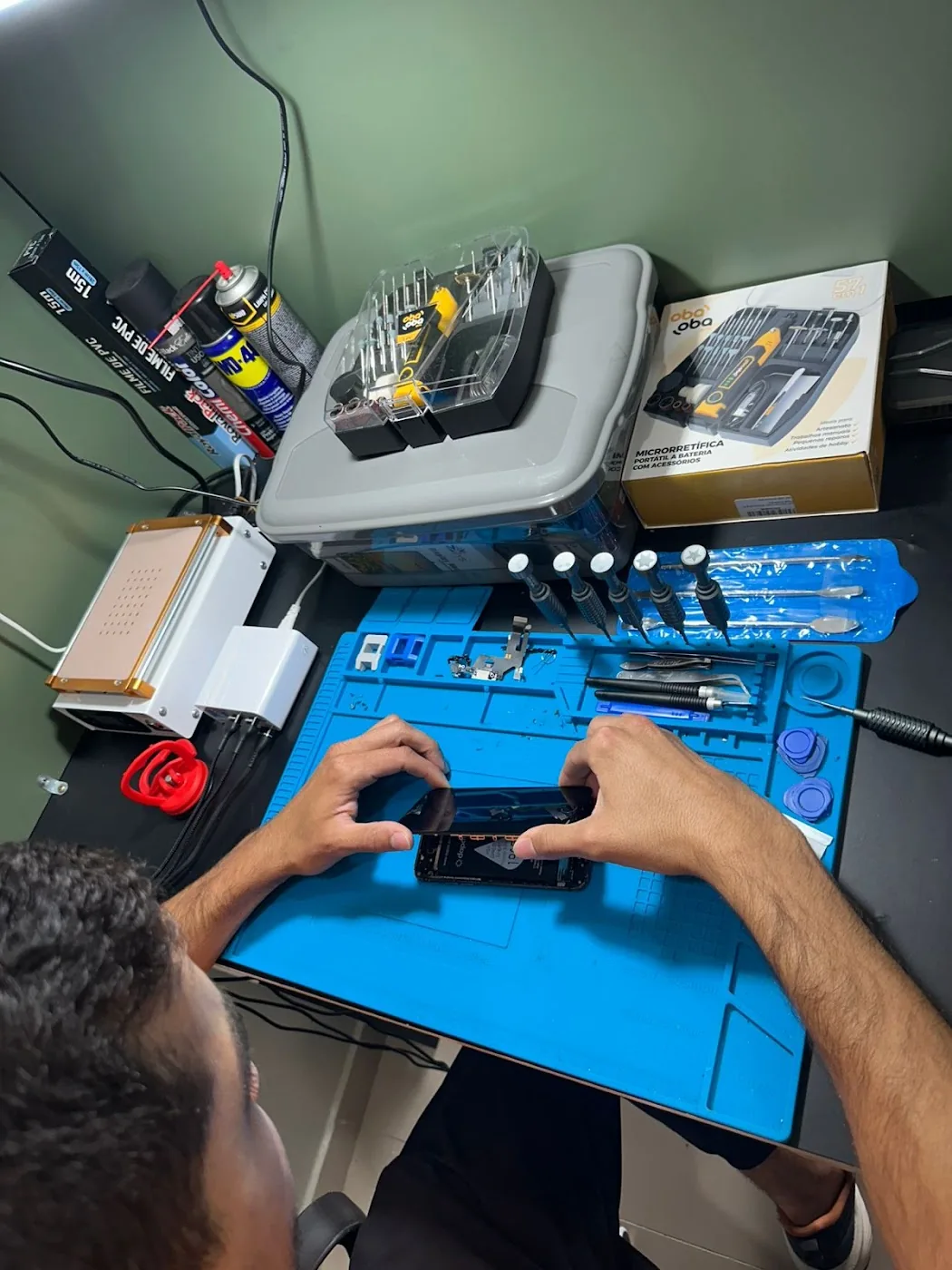 Profissional da Campeche Cell trabalhando na bancada da loja